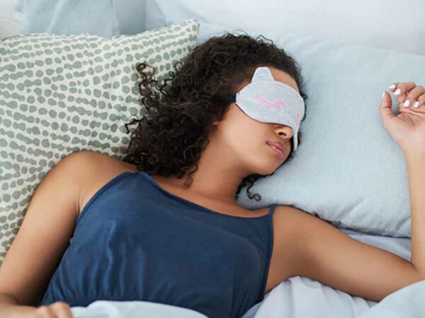 black woman sleeping in bed with a mask